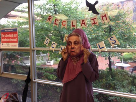 After filling out two postcards addressed to her state lawmakers urging them to fund MAP grants and education, an NEIU student dons a Mayor Rahm Emanuel mask for a photo booth protest shot to be posted on social media. | Teresa Albano / PW