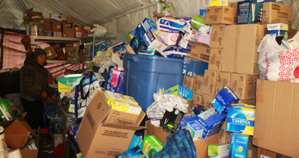 A water protector searches for necessary products through piles of donated supplies. | Michelle Zacarias/PW