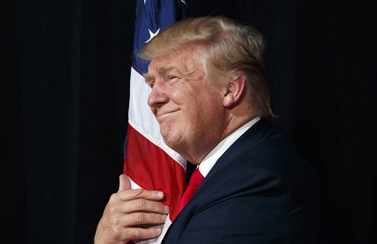 Nationalism is a common element for the global authoritarian right. Here, Republican candidate Donald Trump hugs a U.S. flag at a rally last year. | Evan Vucci / AP